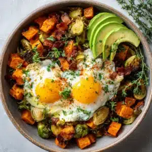 A close-up overhead shot of a savory breakfast skillet filled with crispy sweet potatoes and caramelized Brussels sprouts.
