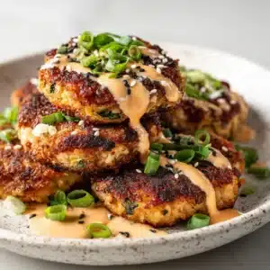 An extreme close-up shot of golden brown tuna patties, showing the crispy panko texture and flaky interior.