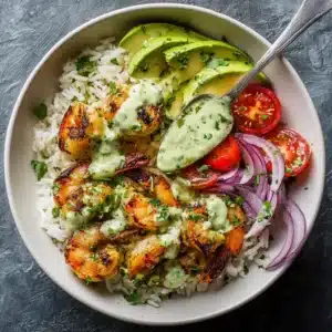 A close-up overhead shot of a healthy shrimp bowl with perfectly cooked shrimp, sliced avocado, and fresh vegetables on a bed of rice.