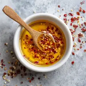 A close-up view of chili infused honey, showing the red pepper flakes suspended in golden honey.