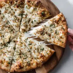 An overhead close-up shot of a rustic white bowl filled with creamy garlic sauce for pizza, ready to be used.