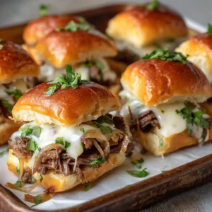 A platter of freshly baked Hawaiian roll cheesesteak sliders, showing the savory steak and pepper filling and melted cheese.