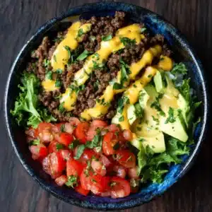 An extreme close-up shot of a healthy cheeseburger bowl, highlighting the juicy ground beef, melted cheese, and fresh lettuce. A perfect low-carb meal.