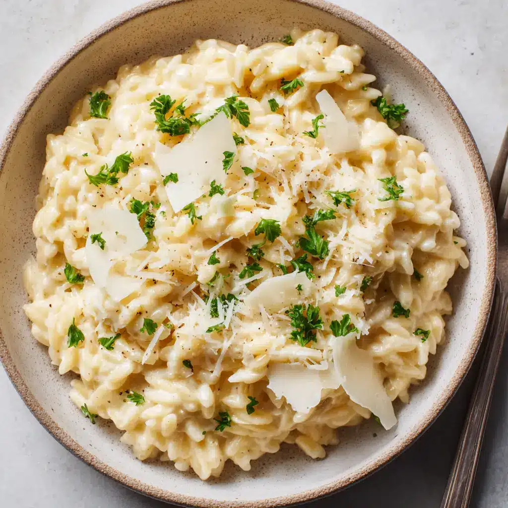 Creamy Garlic Parmesan Orzo generously topped with freshly shaved parmesan cheese curls, raw minced garlic bits, and bright green parsley flakes.
