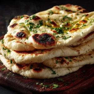 Detailed shot of large bubbles and charred leopard spots on freshly cooked naan bread in a cast iron skillet. (Naan Bread Recipe)