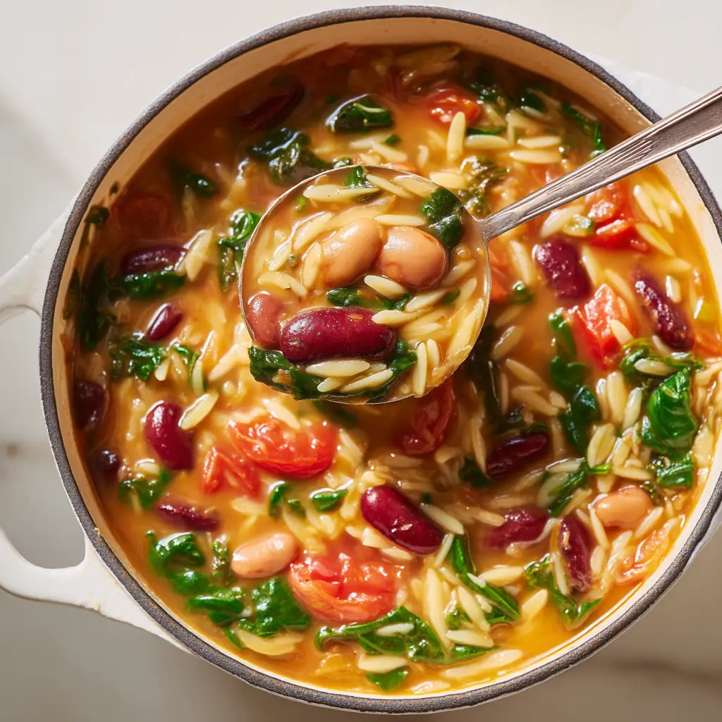 An extreme close-up overhead shot of the healthy orzo pasta salad, showing the texture of the feta, tomatoes, and cucumbers.