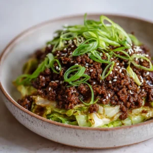 A close-up handheld photo showing the texture of the Low-Carb Mongolian Ground Beef. You can see the glossy sauce on the beef crumbles and the tender-crisp cabbage.