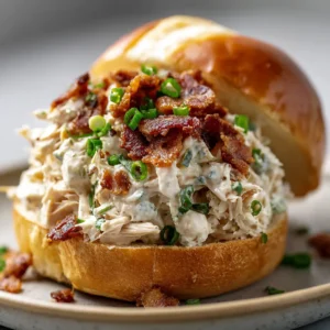 Tender shredded chicken thoroughly mixed in a thick, gooey, melted white cream cheese sauce on a golden brioche bun.