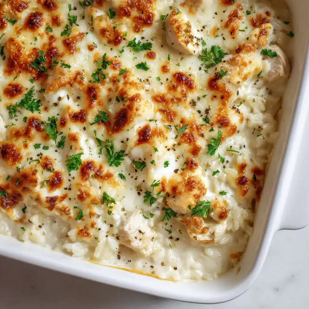 Melted mozzarella and parmesan cheese crust with golden-brown bubbly spots and black pepper. (Dump-and-Bake Chicken Alfredo Rice Casserole)