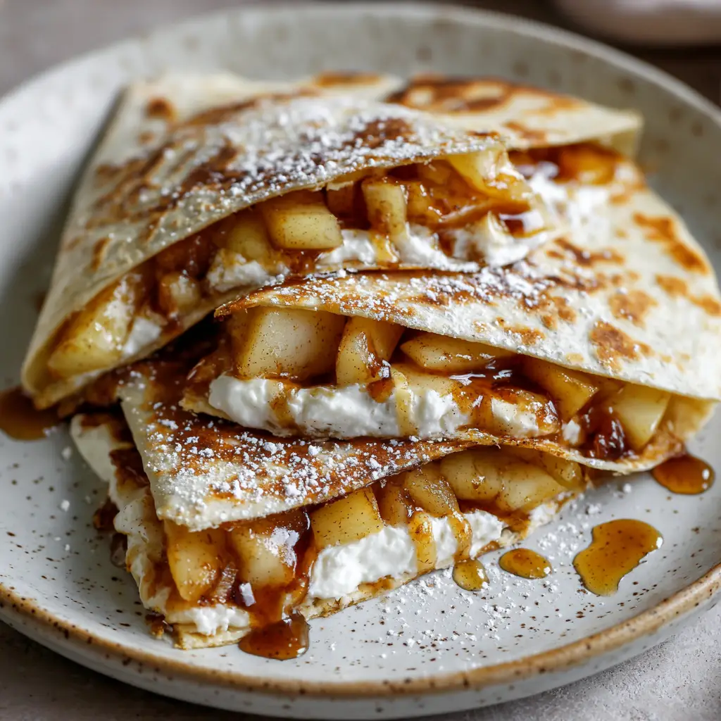 Close up shot of golden brown Apple Cinnamon Breakfast Quesadillas showing caramelized apple filling and melted cream cheese.