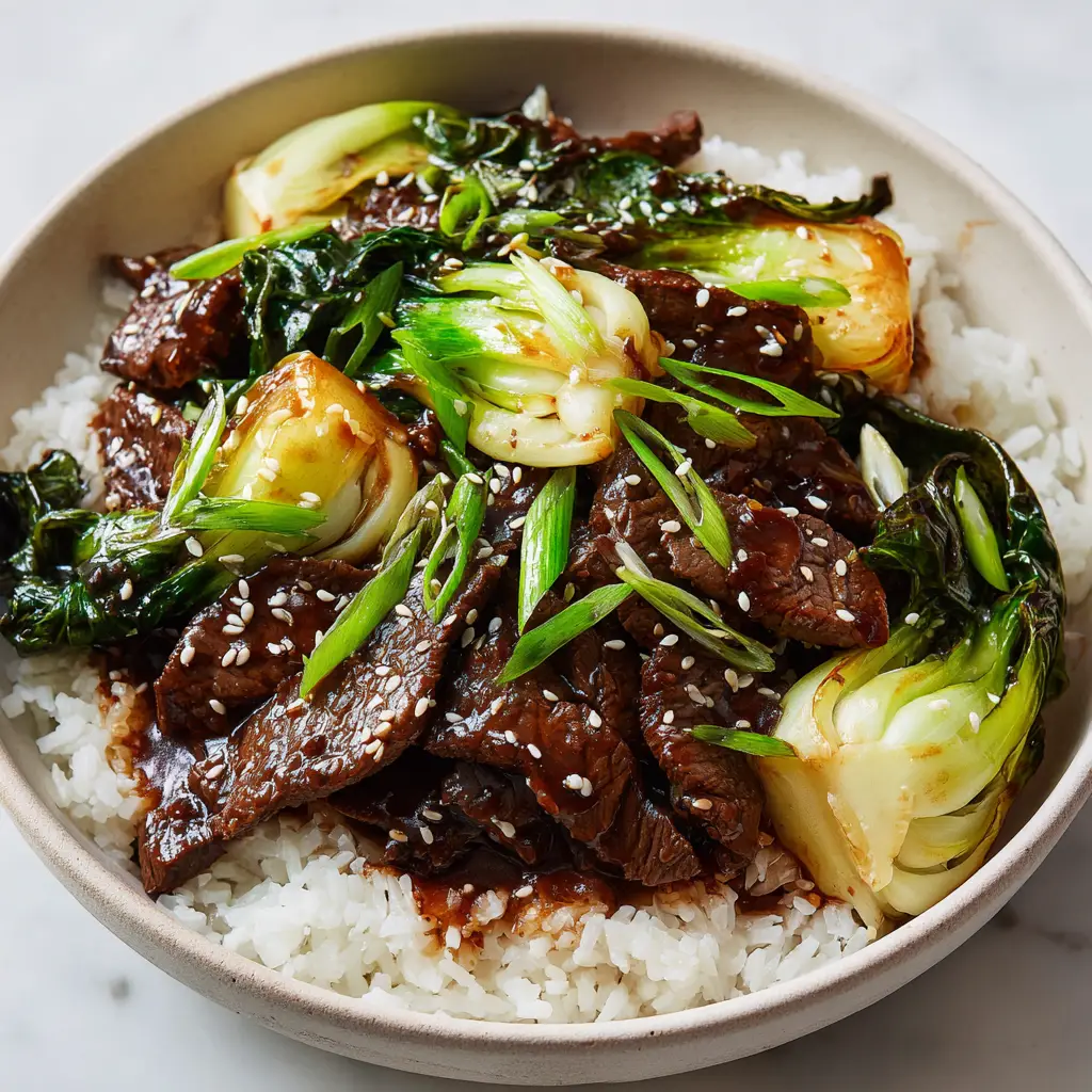 Sizzling beef and bok choy stir-fry in a ceramic bowl, showing the thick glossy dark brown sauce.