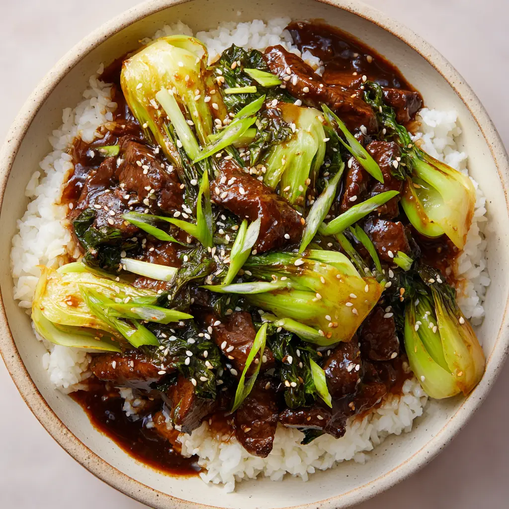 Overhead view of Beef and Bok Choy Stir-Fry garnished with sesame seeds and green scallions.