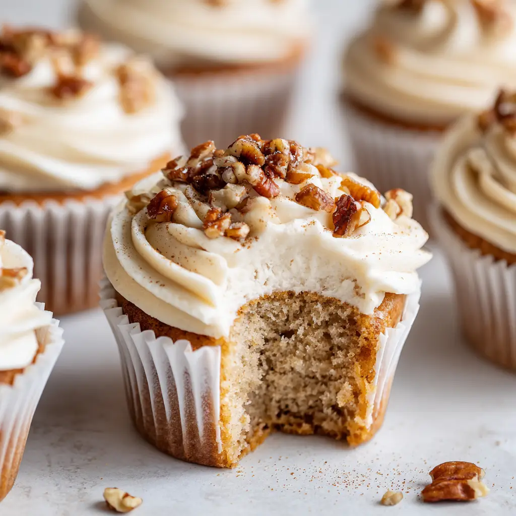 Banana Cinnamon Pecan Cupcakes: The Ultimate Fluffy Bakery-Style Recipe 1 Banana Cinnamon Pecan Cupcakes with a generous swirl of pale beige cream cheese frosting and cinnamon dusting.