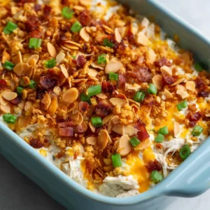 A close-up shot of the creamy shredded chicken base of the Neiman Marcus Chicken Casserole with melted cheddar.