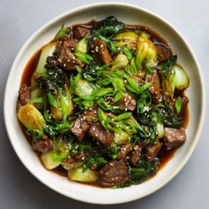 Close-up of seared beef strips and wilted bok choy leaves in a savory brown sauce. (Beef and Bok Choy Stir Fry)