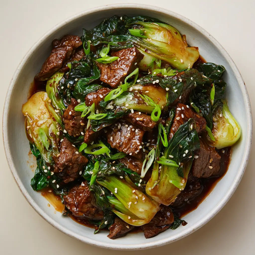 Overhead view of Beef and Bok Choy Stir Fry garnished with white sesame seeds and scallions.