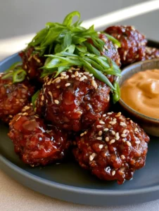 Close-up of seared Korean BBQ Meatballs with a translucent dark red gochujang glaze and fresh scallions.