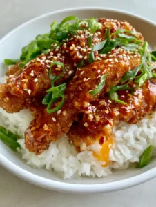 A handheld smartphone photo showing four long Sweet and Spicy Cod Strips on a bed of jasmine rice in a white bowl.