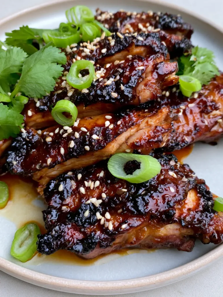 Macro close-up of Garlic Miso Chicken slices stacked on a plate with visible garlic bits in the glaze.